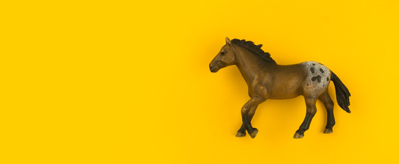 Toy horse made of plastic on a yellow background.