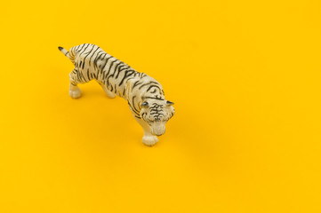 White albino tiger toy made of plastic on a yellow background.