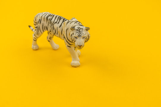 White albino tiger toy made of plastic on a yellow background.