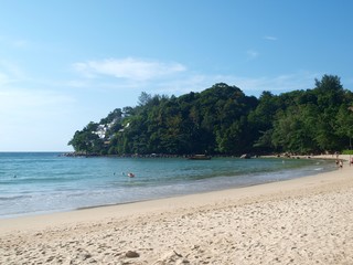 Fototapeta na wymiar Tropical sandy beach with resting swimming people in Thailand. Thai resort at famous Phuket island. Paradise summer and winter vacation. Panoramic view. Seascape. The perfect place to relax.