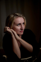 Fototapeta premium Portrait of a middle-aged woman in the room. Photography in the Studio. Photo shoot in a dark key