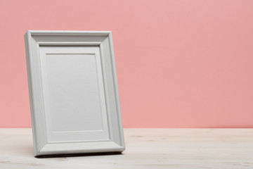 white frame on white desk near pink wall