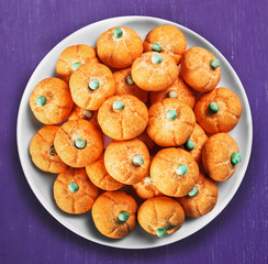 marshmallows in the shape of a pumpkin for the holiday Halloween on a plate on a lilac background
