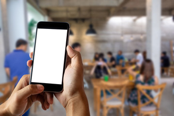 Hand holding white mobile phone with blank white screen  in cafe.