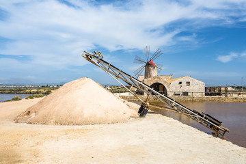 Heap of salt with a typical windmill at Trapani and Paceco salt evaporation ponds, Sicily, Italy