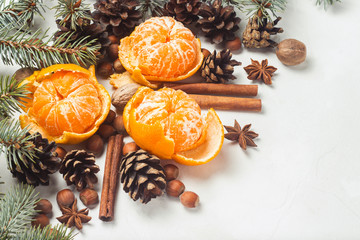 Fototapeta premium Tangerines without peel, Christmas tree branches, spices, cinnamon, cones on a white stone background. Concept of Christmas, New Year, Mulled Wine