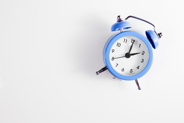 Alarm clock on a white background with shadows. Two o'clock in the afternoon. View from above.