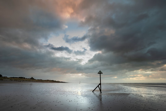 Stunning Winter sunrise over West Wittering beach in Sussex England with wind blowing sand across the beach