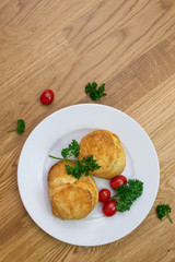 Egg buns on white plate with parsley and mini tomatoes on wooden background