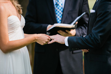 Obraz na płótnie Canvas bride putting on wedding ring onto groom during ceremony