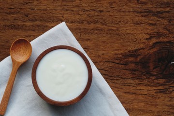 Plain organic yogurt in wooden bowl and wood spoon on wood texture background