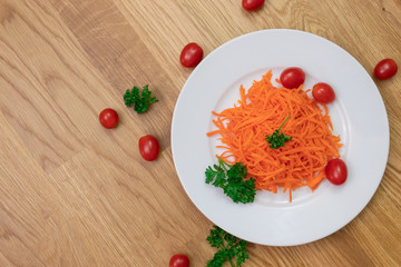 Ground carrots, tomatoes and parsley on white plate and items all over the table