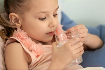 Little girl taking pill in bed