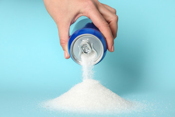 Woman pouring sugar from can on color background