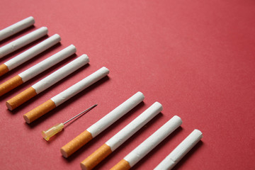 Cigarettes with syringe needle on color background. Concept of addiction