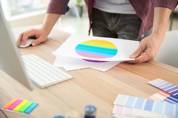 Young designer with color palettes working in office