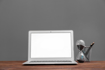 Modern laptop on table against grey wall