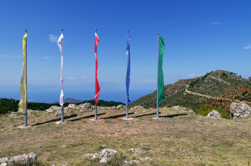 Buddhist flags of 5 colors on the background of mountains, blue sky and the sea. Landscape of...