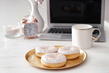Tray with tasty doughnuts on white wooden table