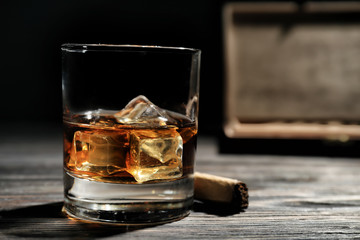 Glass of whiskey and cigar on wooden table