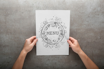 Female hands with menu on grey background - obrazy, fototapety, plakaty