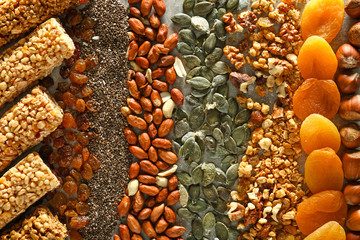 Tasty granola bars and ingredients on table