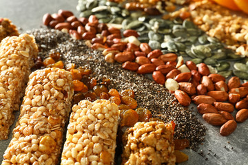 Tasty granola bars and ingredients on table, closeup