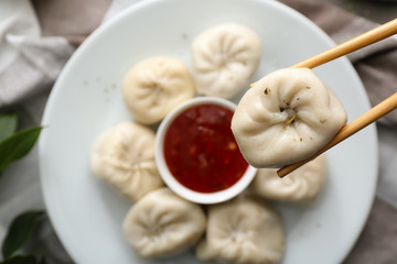 Chopsticks with tasty Chinese dumpling over plate