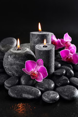 Fototapeta na wymiar Candles, flowers and spa stones on dark background