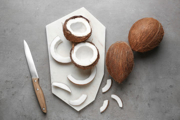 Composition with ripe coconuts and cutting board on grey background