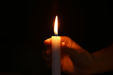 Female hand with burning candle in darkness