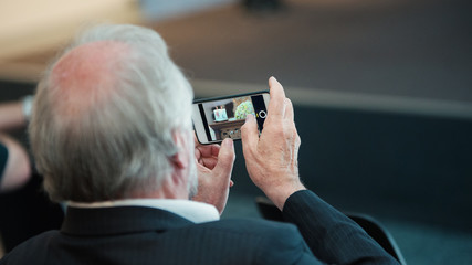 man with mobilephone makes pictures and is filming indoor