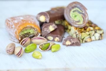 Eastern Turkish sweets with pistachios on a white wooden background. Fragrant baklava, chocolate, sweets with pistachios.