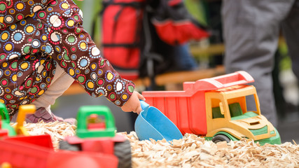 Fototapeta premium Spielendes Kind am Spielplatz mit Schäufelchen und Schpielzeug
