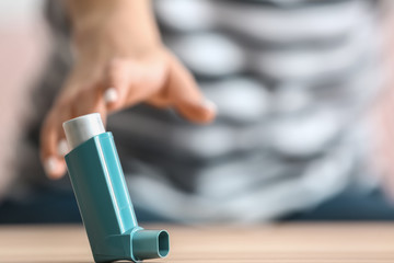 Young woman with asthma attack taking inhaler from table, closeup - obrazy, fototapety, plakaty