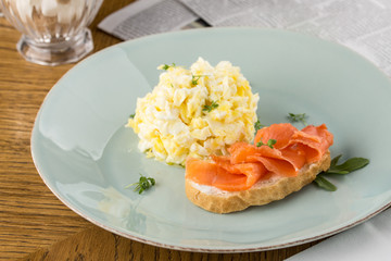 Scrambled egg and smoked salmon on toast on wooden table