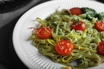 Plate of tasty color pasta with tomatoes on table, closeup