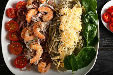 Plate with tasty pasta, vegetables, shrimps and cheese on table, closeup