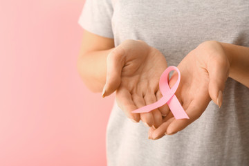 Woman with pink ribbon on color background. Breast cancer awareness concept