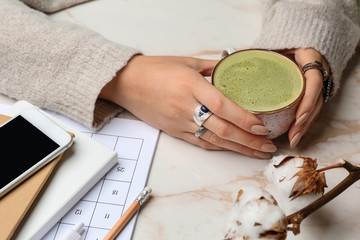 Woman with cup of healthy matcha tea at table