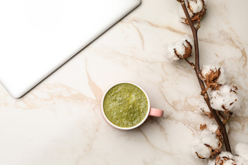 Cup of healthy matcha tea and laptop on table