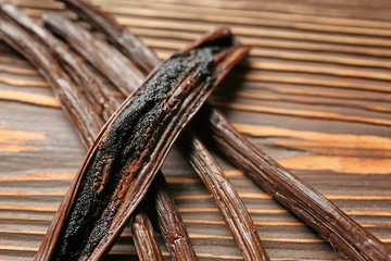 Aromatic vanilla sticks on wooden background, closeup