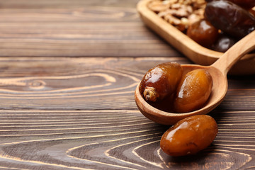 Spoon with sweet dried dates on wooden background