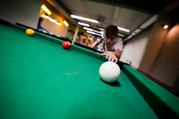 Handsome young guy playing billiards