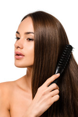 Fototapeta premium beautiful girl combing long hair with hairbrush isolated on white