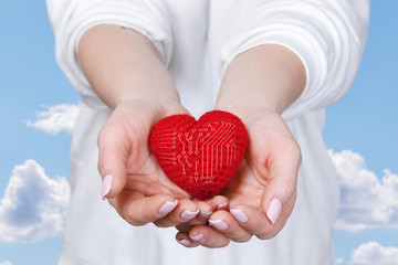 A woman is holding a heart in her palms.