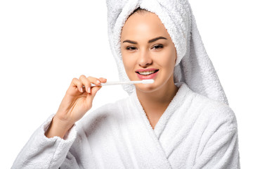 beautiful girl in bathrobe holding toothbrush, smiling and looking at camera isolated on white