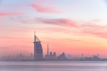 Stunning view of Dubai skyline from Jumeirah beach to Downtown lighted with warm pastel sunrise...