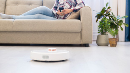 girl resting at home on the couch, while the robot vacuum cleaner. concept time for yourself. smart...
