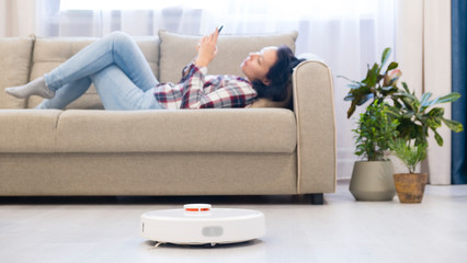 girl resting at home on the couch, while the robot vacuum cleaner. concept time for yourself. smart...